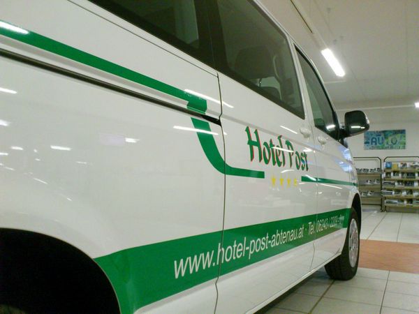 Hotel Post Abtenau - VW Bus mit gegossener gruener und gelber Hochleistungsfolie beschriftet